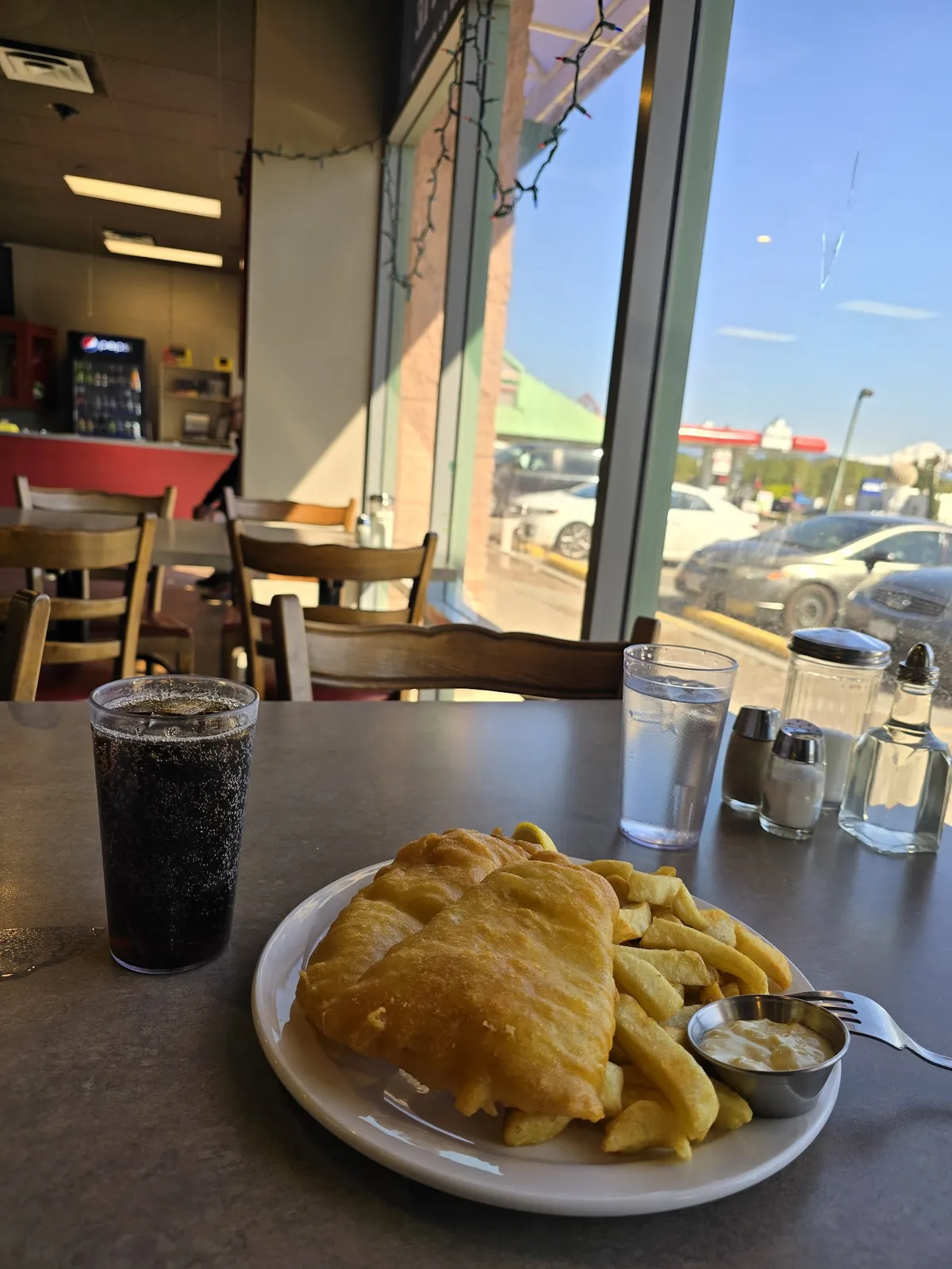 Plate of fish and chips with drinks on a table